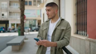 Sokakta akıllı telefon kullanan, kendine güvenen genç bir İspanyol.