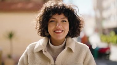 Young hispanic woman smiling confident using professional camera at street