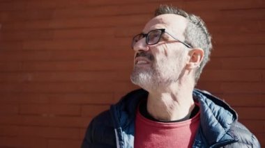 Middle age man smiling confident looking to the sky at street