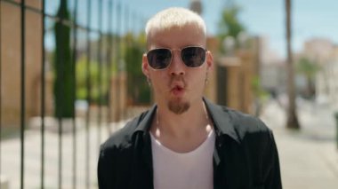 Kafkasyalı genç adam kendine gülerek komik hareketler yapıyor.