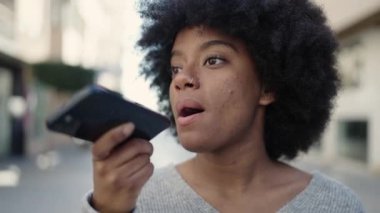 Afro-Amerikalı kadın gülümsüyor. Akıllı telefondan konuşuyor.