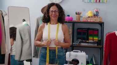 Middle age woman tailor smiling confident standing at clothing factory