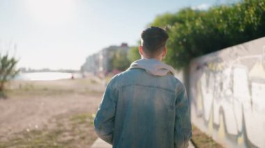 Arkadan bakan genç İspanyol adam sokakta yürüyor.