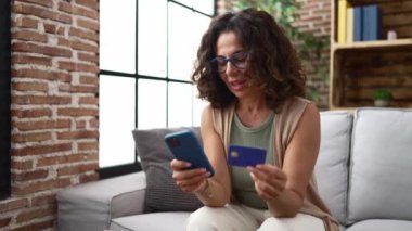 Middle age hispanic woman shopping online from smartphone