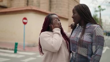 Two african american women smiling confident speaking at street