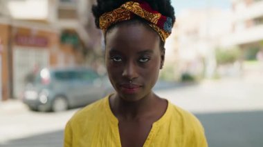 Rahat yüzü olan genç Afro-Amerikalı kadın sokakta dikiliyor.