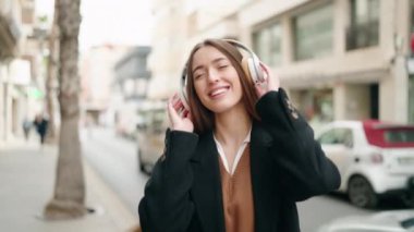 Genç İspanyol kadın sokakta müzik dinlerken kendinden emin gülümsüyor.