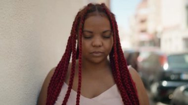 Afro-Amerikalı kadın gülümsüyor. Kendinden emin bir şekilde caddeye bakıyor.