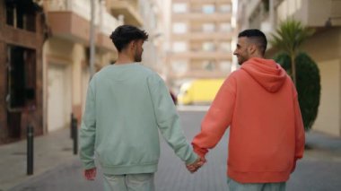 Genç İspanyol çift gülümsüyor. Birbirlerine sarılıyorlar. Sokakta yürüyorlar.