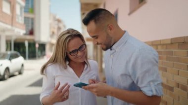 Kadın, erkek, anne ve kız sokakta akıllı telefon kullanıyor.