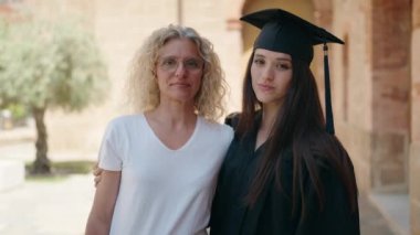 Two women mother and graduated daughter hugging each other at campus university