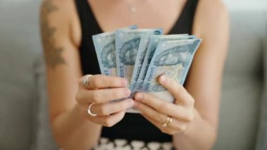 Genç bir kadın evdeki 100 bin dolarlık banknotları sayıyor.