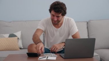 Genç İspanyol adam evde dolar sayıyor.