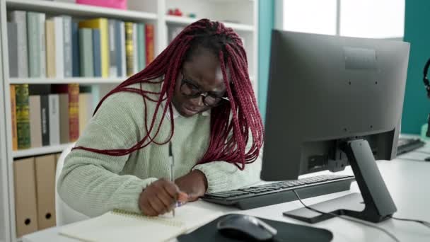 大学図書館で背痛を持つコンピュータを使用して編組髪の学生を持つアフリカの女性 — ストック動画