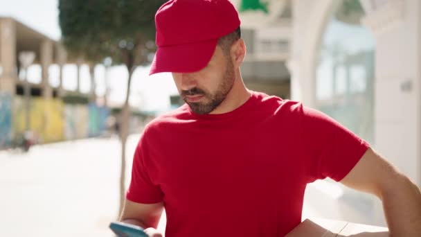 Young Hispanic Man Deliveryman Holding Package Talking Smartphone Street — Stock Video