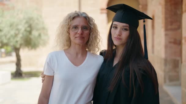 キャンパス大学で抱き合っている2人の女性の母親と卒業生の娘 — ストック動画
