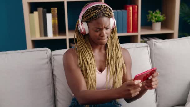 非洲裔美国妇女坐在家里的沙发上玩电子游戏 — 图库视频影像