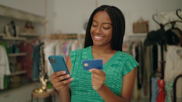 衣料品店でスマートフォンやクレジットカードを使用するアフリカ系アメリカ人女性の顧客 — ストック動画