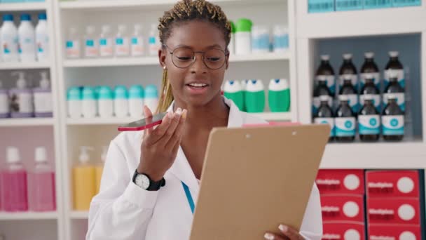アフリカ系アメリカ人女性薬剤師が薬局でスマホ読み取り文書について語る — ストック動画