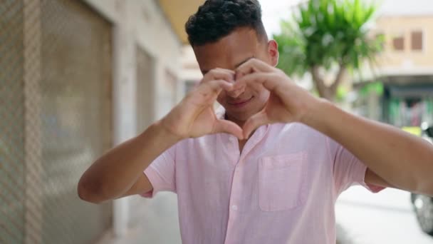 Jovem Latino Sorrindo Confiante Fazendo Gesto Coração Com Mãos Rua — Vídeo de Stock