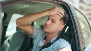 Young hispanic man unhappy driving car at street