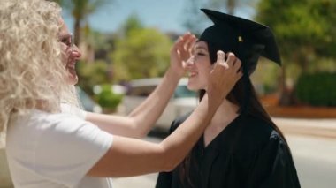 Two women mother and graduated daughter standing together at street
