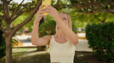 Genç sarışın kadın parkta selfie çekiyor. 