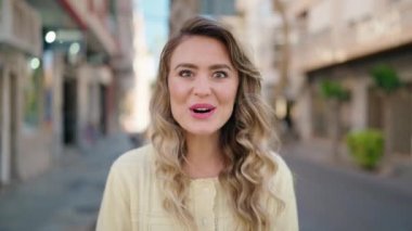 Genç sarışın kadın gülümsüyor.