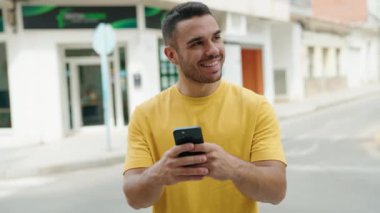 Sokakta akıllı telefon kullanan, kendine güvenen genç bir İspanyol.