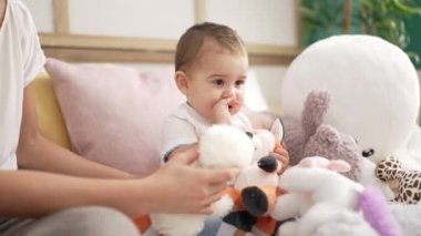 Sevimli çocuk evdeki kanepede oturup bebek ısırıyor.