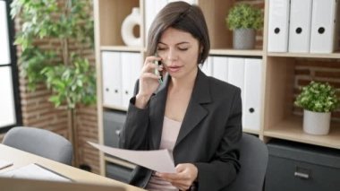 Kafkasyalı genç bir iş kadını ofisteki akıllı telefon okuma belgeleriyle konuşuyor.