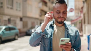 Sokakta müzik dinlerken kendinden emin gülümseyen İspanyol genç adam.