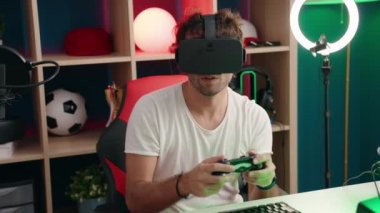 Sanal gerçeklik gözlüğü ve müzik stüdyosunda joystick kullanarak video oyunu oynayan İspanyol asıllı genç adam.