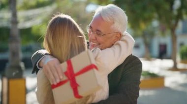 Orta yaşlı çift parkta birbirlerine sarılıyorlar.