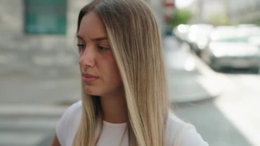 Young beautiful hispanic woman looking to the camera with serious expression at street