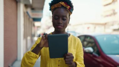 Sokakta dokunmatik ped kullanan, kendine güvenen genç Afro-Amerikan kadın.