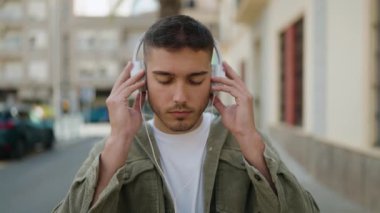 Sokakta müzik dinlerken kendinden emin gülümseyen İspanyol genç adam.