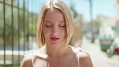 Sokakta kendine güvenen genç sarışın kadın gülümsüyor