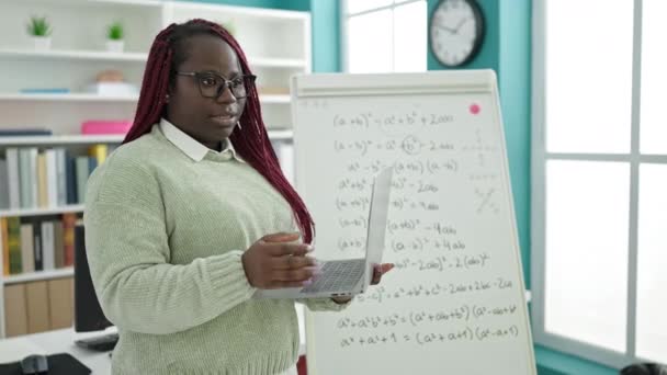 編組の髪の先生を持つアフリカの女性は大学図書館で数学のレッスンを教える — ストック動画