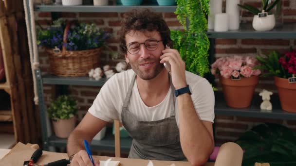 Ung Latinamerikansk Man Florist Talar Smartphone Skriver Anteckningsbok Blomsteraffär — Stockvideo