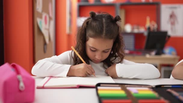 Adorable Hispanic Girl Student Sitting Table Writing Notebook Classroom — Stockvideo