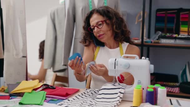 中年妇女裁缝在服装厂用智能手机拿着布说话 — 图库视频影像