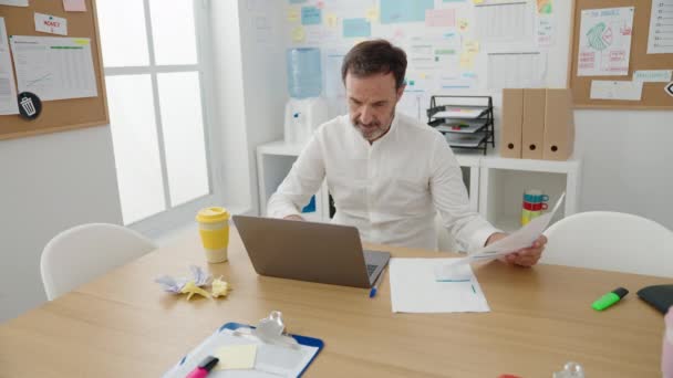 オフィスでノートパソコン読み取り文書を使用している中年の男性のビジネスワーカー — ストック動画
