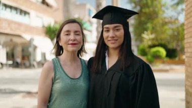 İki kadın anne ve mezun kız sokakta öpüşerek diploma alıyorlar.