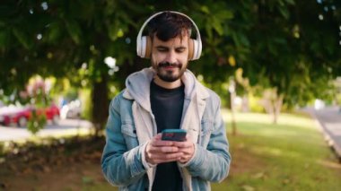 Young hispanic man smiling confident listening to music at park