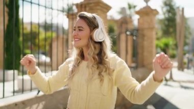 Sokakta müzik dinleyen kendine güvenen genç sarışın kadın.