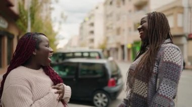 Two african american women smiling confident speaking at street