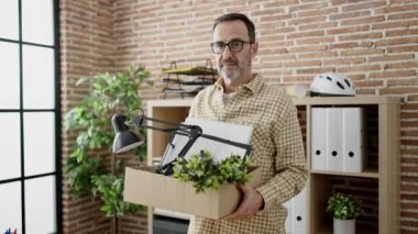 Middle age man business worker dismissed holding cardboard box at office