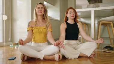 Yoga yapan iki kadın evde yerde oturuyor.