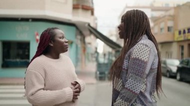 Two african american women smiling confident speaking at street